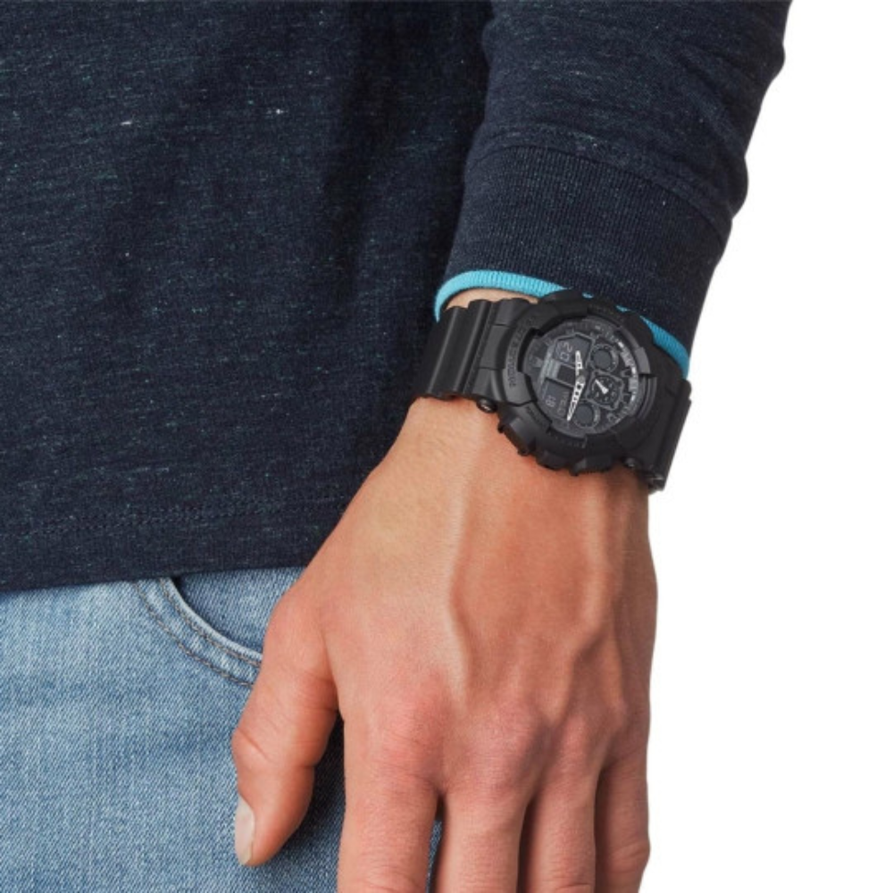 Montre G-Shock GA-100 noire de Casio avec cadran en verre minéral, boîtier et bracelet en résine, résistance magnétique et plusieurs fonctionnalités pratiques.